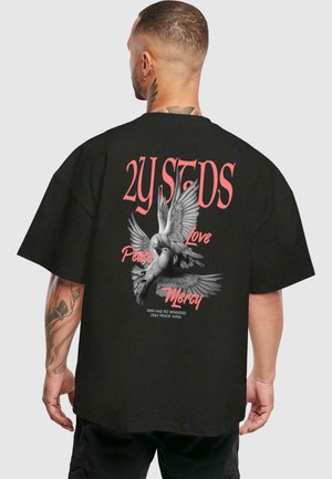 Schwarzes, übergroßes T-Shirt mit einem Grafikdesign von Tauben und Text in Pink und Weiß: "2Y STDS", "Frieden", "Liebe", "Barmherzigkeit".