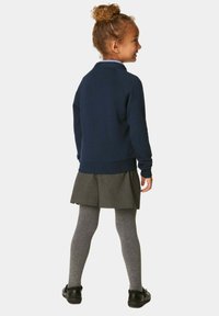 Felpa blu navy, gonna a pieghe grigia, leggings grigi e scarpe nere. Tessuto testurizzato con polsini e orlo a coste. Dettaglio del colletto visibile.