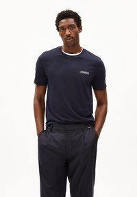 Marineblauwe T-shirt met korte mouwen, voorzien van een witte ronde hals en een klein geborduurd logo op de borst. Glad katoen, relaxed fit.