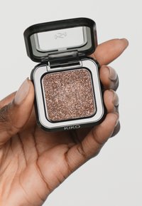 Firkantet kompakt med glitrende kobberøyenskygge i et svart plastetui, med en klar lokk og merkevarenavnet "KIKO" på forsiden.