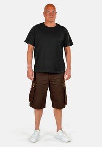 Čierne tričko s krátkym rukávom v kombinácii s hnedými cargo šortkami s bočnými vreckami. Doplnené bielymi teniskami. Jednoduchý, neformálny outfit.