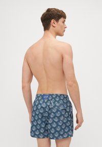 Blaue Badeshorts mit einem weißen maritimen Muster, elastischem Bund mit Etikett und einer Gesäßtasche. Glattes, leichtes Gewebe.