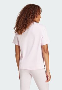 Tricou din bumbac roz deschis, cu o croială lejeră, mâneci scurte și decolteu rotund. Textură netedă, cu cusături minime pe spate.