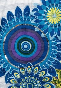 Niebieska i żółta tkanina w kwiaty prezentuje koncentryczne okręgi w kolorze fioletowym i zielonym, otoczone cekinowymi akcentami oraz misternymi wzorami.