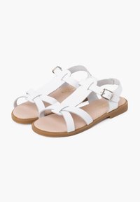 White leather sandals with crisscross straps, adjustable buckle, and a tan rubber sole. Flat design and smooth texture.