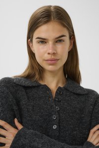 Cardigan en laine gris foncé avec un large col, un devant boutonné et un tissu texturé, présentant des boutons noirs le long du plastron.