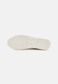 White rubber shoe sole with wave pattern. Rounded shape, flat design, and rectangular logo label in the center. Smooth texture throughout.