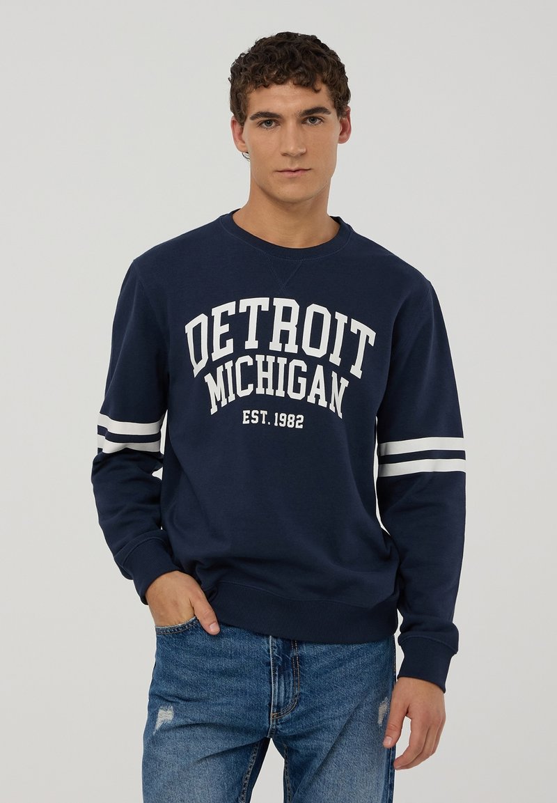 Granatowy sweatshirt z napisem "DETROIT MICHIGAN" oraz "EST. 1982" w kolorze białym, z białymi paskami na rękawach.