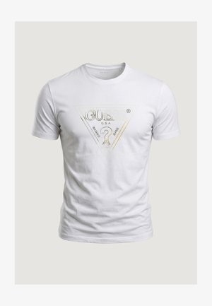 Valge lühikeste varrukatega T-särk, mille rinnal on metallik-kuldne Guessi logo kolmnurk ja küsimärk, kujutatud neutraalsel taustal.