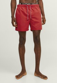 Rode zwemshorts met een trekkoord in de taille en een contrasterende grijze koord. Glad materiaal, knielange snit, minimale stikdetails.
