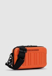 Borsa rigida arancione con design testurizzato, dotata di tracolla regolabile nera e chiusura con cerniera. Logo in rilievo sul davanti.