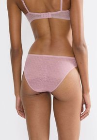 Różowe stringi damskie wykonane z lekkiej, teksturowanej tkaniny z powtarzającym się wzorem oraz minimalistycznym elastycznym pasem.