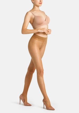 Beige BH mit dünnen Trägern und tiefem V-Ausschnitt, kombiniert mit transparenten, beigen Strumpfhosen und pinken Wildleder-Stilettos, an einem Modell.