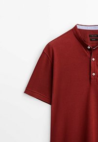 Polo rouge foncé à manches courtes avec patte de boutonnage et détail du col intérieur bleu clair.