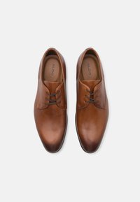 Brune læderherresko med en glat overflade, rund tå og snørebåndsdesign. Diskrete syninger fremhæver det elegante udseende.