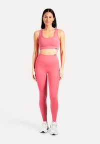 Rosa sport-bh och högmidjade leggings i elastiskt tyg med sömlös design och diskreta logodetaljer.