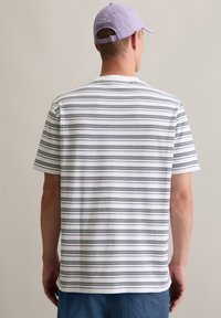 Gestreiftes Kurzarm-T-Shirt in Weiß mit schwarzen und grauen Streifen. Weicher, leichter Stoff. Rückansicht mit rundem Halsausschnitt und lockerer Passform.