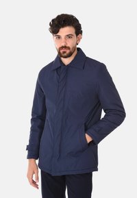 Giacca leggera, resistente all'acqua, blu navy con colletto classico, zip frontale e tasche laterali. Texture liscia, design minimalista.