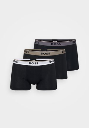 Trzy pary bokserek w kolorze czarnym, z elastycznym paskiem z logo; jedna para z szarym paskiem, druga z beżowym, a jedna jest całkowicie biała.