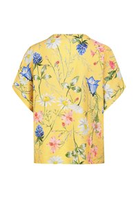 Kurzarmhemd mit Blumenmuster auf gelbem Hintergrund, das verschiedene bunte Blumen zeigt und eine lässige, kastige Form hat.