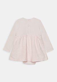 Langärmeliger Baby-Overall mit rosa Blumen-Spitzenrock-Overlay und Druckknöpfen hinten auf einfarbig zartrosa Stoff.