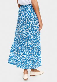 Fustă midi florală albastră cu un design în straturi. Fabricată dintr-un material ușor, având modele florale albe. Talie elastică și o ușoară ondulație la tiv.