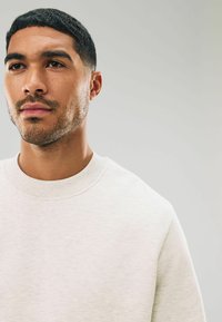 Lichtgrijze sweatshirt met ronde hals en een gestructureerde stof. Heeft een geribbelde kraag en naden, minimalistisch ontwerp zonder zichtbare logo's.