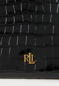 Čierna lesklá kožená taška s krokodíľou textúrou, akcentovaná zlatým logom "RLL" v dolnom rohu, zdôrazňujúca elegantný dizajn.