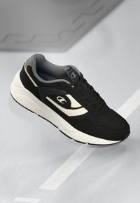 Black and white sneaker with a textured upper and smooth midsole, featuring a logo on the side and a rounded toe design.