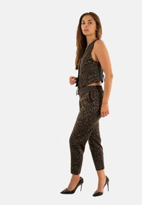 Leopardmönstrad ärmlös topp och matchande byxor i brunt och svart, med en avslappnad passform och dragsko i midjan. Bärs med svarta högklackade skor.