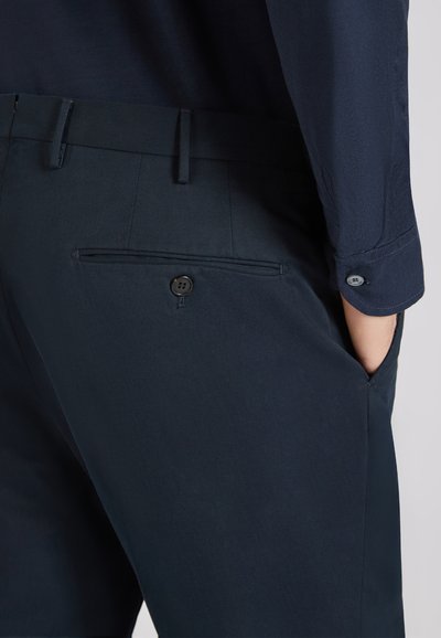 Pantalons navy en tissu texturé, avec une poche arrière à bouton et des poches latérales, coupe ajustée.