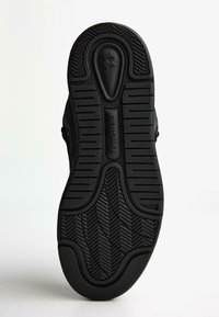 Talpa de sneaker neagră din cauciuc texturat, având un model în zig-zag pentru aderență și marca "Bershka" embosată aproape de toc.