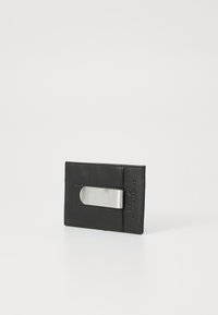 Portefeuille en cuir noir avec un accent métallique argenté, de forme rectangulaire, texture lisse, avec une découpe pour l'accès aux cartes.