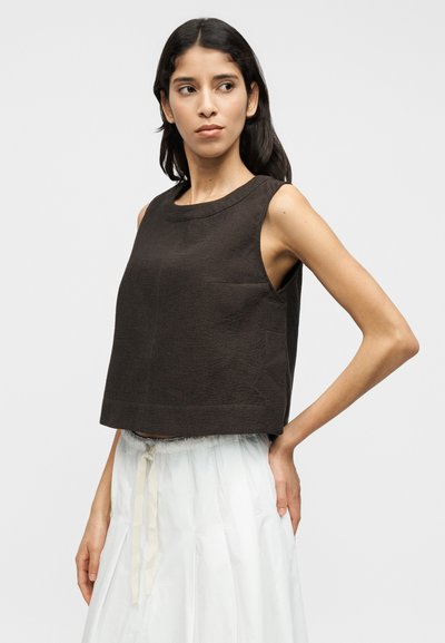 Καφέ κοντό τοπ χωρίς μανίκια με στρογγυλή λαιμόκοψη, διαθέτει μικρή μπροστινή τσέπη και άνετη εφαρμογή.