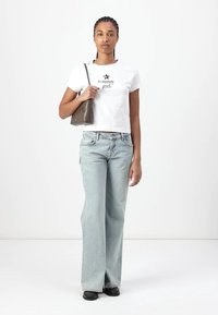 Hvit kort t-skjorte med teksten "tommy girl", lyseblå vide jeans og en liten olivengrønn håndveske. Svarte sko fullfører antrekket.