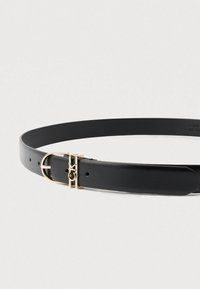 Μαύρη δερμάτινη ζώνη με γυαλιστερή χρυσή αγκράφα που φέρει λογότυπο. Η ζώνη έχει λεία υφή και πολλές τρύπες για ρυθμιζόμενο μέγεθος.