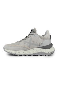 Scarpa sportiva grigia con un mix di materiali in suede e mesh, tomaia texturizzata, suola intermedia bianca a pois in contrasto e suola esterna in gomma flessibile.