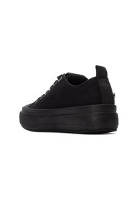Zapatillas de ante negro con suela de goma gruesa, punta redonda y diseño de cordones. Presentan una pestaña trasera y una textura minimalista y suave.