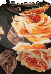 Tissu noir avec de grandes impressions de roses orange et crème et des feuilles marron, avec un col transparent à volants.