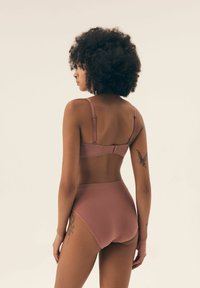 Bra and high-waisted underwear set in soft pink fabric, featuring adjustable straps and hook-and-eye closure, with ribbed texture.