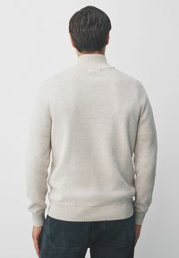 Suéter de punto color beige claro con cuello alto, puños acanalados y dobladillo. La tela parece suave y texturizada, adecuada para el uso casual.
