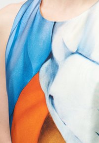 Πολύχρωμο τοπ με halter neck, με έντονα μοτίβα σε μπλε, πορτοκαλί και λευκό. Λείο ύφασμα με εφαρμοστό σχέδιο.