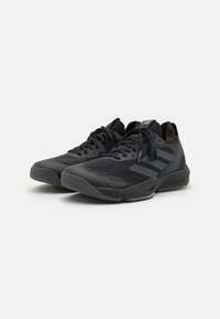 Scarpe sportive nere con una tomaia testurizzata e traspirante, lacci piatti e suola in gomma con motivi antiscivolo. Tre strisce sui lati.
