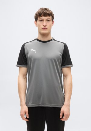 Szürke sport póló fekete ujjaival, könnyű anyagból készült. Kerek nyakkivágással és fehér logóval a mellrészen. Sima textúrájú.