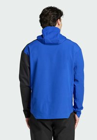 Blauwe hoodie met zwarte mouwen, gemaakt van zacht materiaal. Beschikt over een hoge kraag en elastische manchetten voor een snug fit.