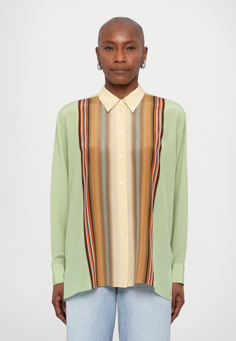 Camisa de manga larga con una tela verde claro y un patrón de rayas verticales multicolores en el centro, rematada con un cuello beige.