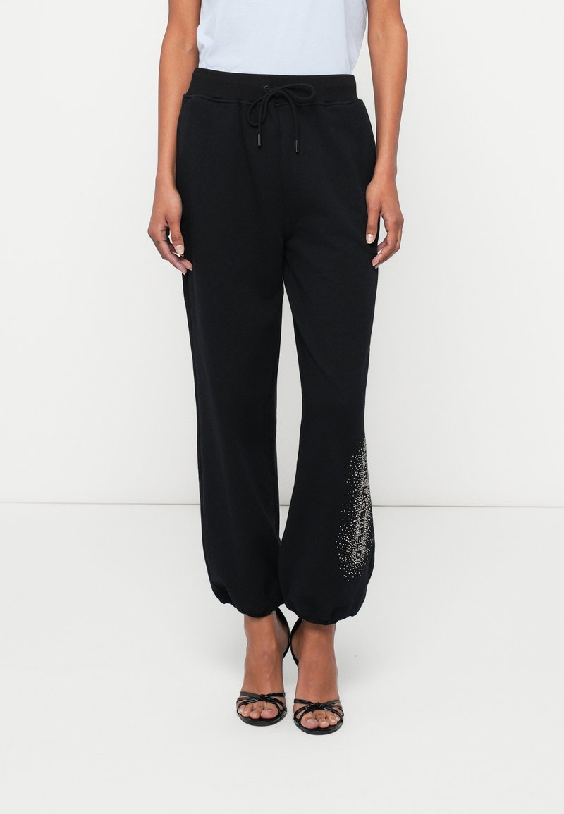 Μαύρο φόρεμα με tapered πόδι, ρυθμιζόμενη μέση με κορδόνι και διακοσμητικό μοτίβο μικρών μεταλλικών κουκίδων στο κάτω μέρος του ποδιού.