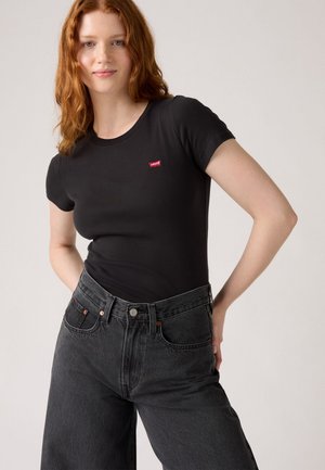 Zwarte getailleerde T-shirt met korte mouwen en een klein rood Levi's-logo. Gecombineerd met losse zwarte hoge taille spijkerbroeken, met een klassieke denimmerk.