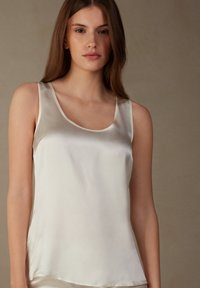 Crème satijnen tanktop met een ronde hals en brede bandjes, met een gladde textuur en een ontspannen pasvorm. Geen zichtbare patronen of accenten.