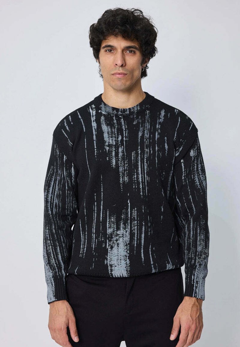 Pull en tricot noir avec un motif abstrait de coups de pinceau gris clair, col rond et manches longues. Texture douce, coupe décontractée.